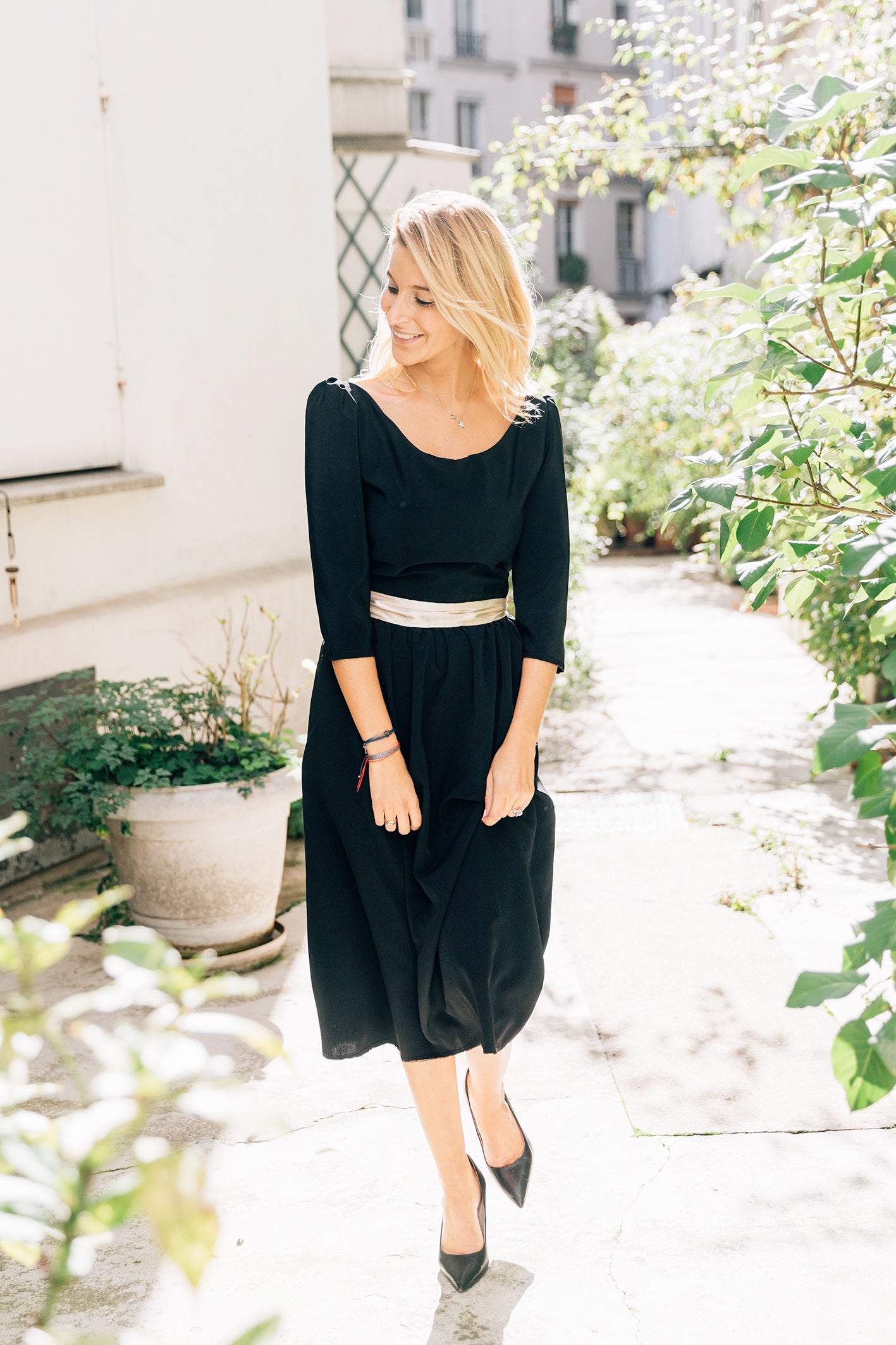 Robe 'Solene' en soie noire avec ceinture dorée, vue complète en mouvement de la robe.