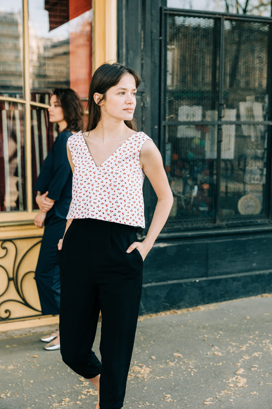 Top 'Jade' sans manches, décolleté V en piqué de coton blanc avec motif cerises, porté par un modèle