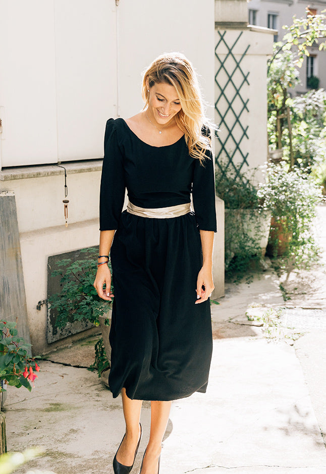 Robe 'Solene' en soie noire avec ceinture dorée, vue complète de l'avant. Longueur mi-mollet et col rond.