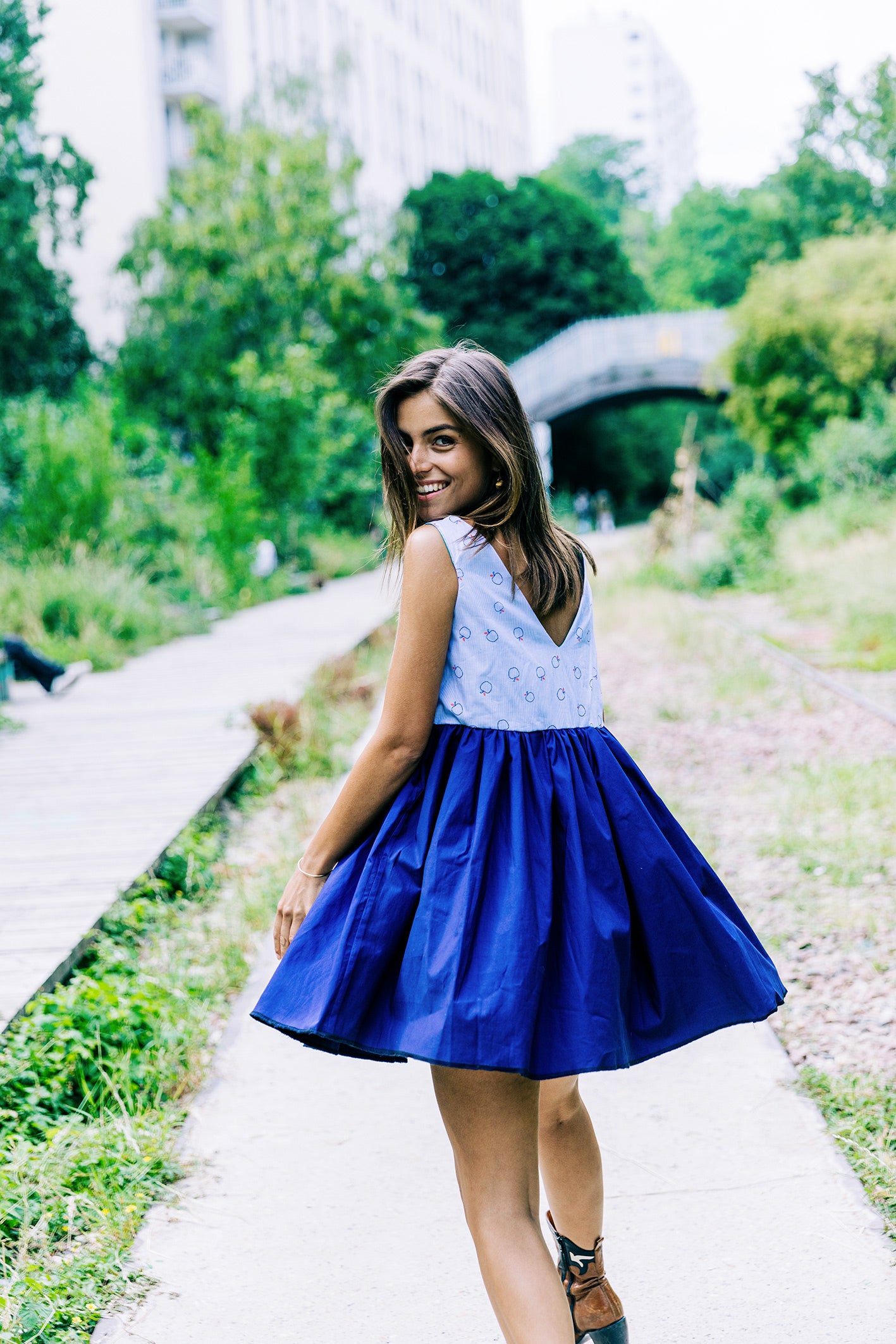 Robe 'Théa' en coton bleu marine et bleu clair avec motifs de pommes rouges, vue complète de dos avec le décolleté en V un peu plus profond qu'a l'avant.