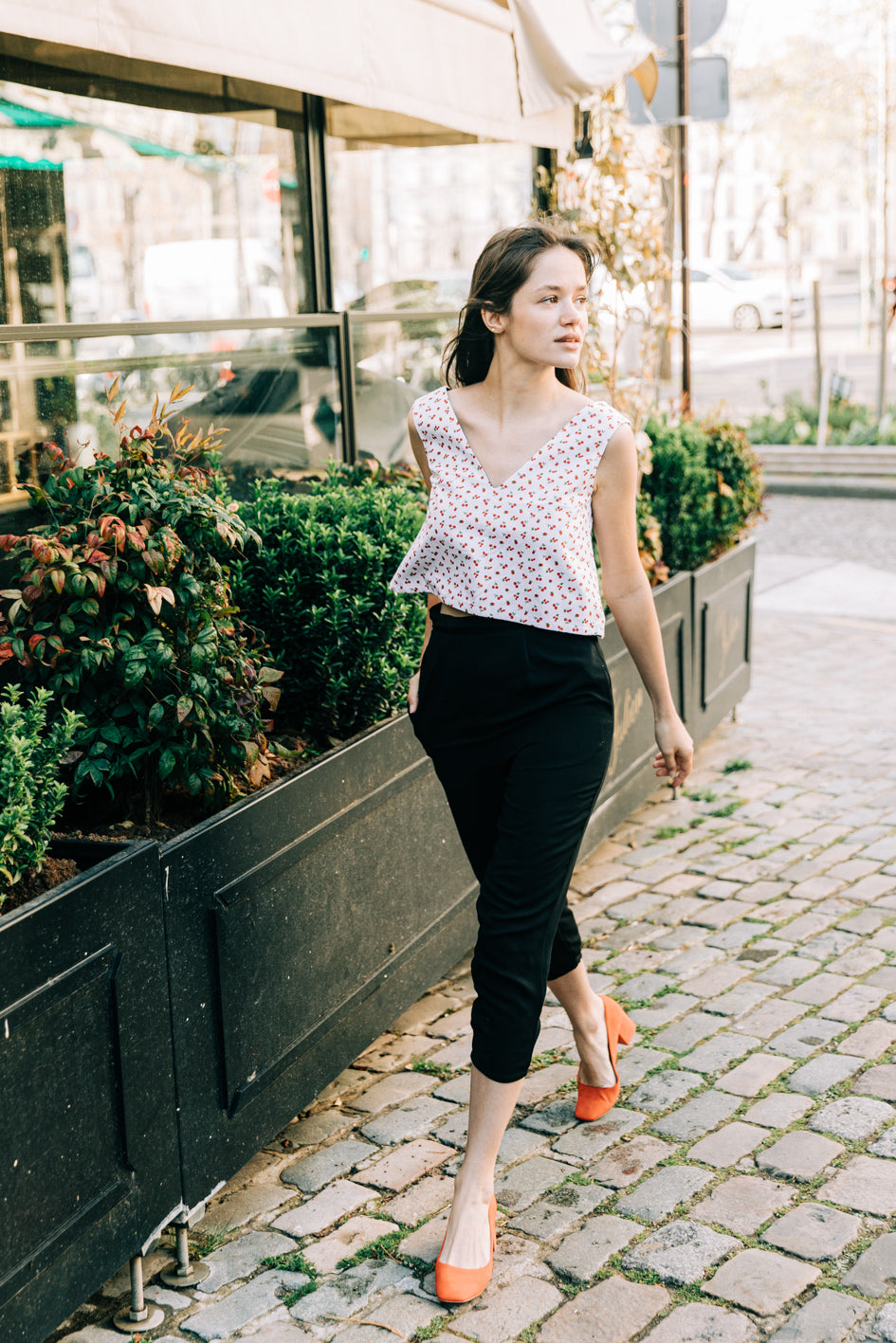 Top 'Jade' sans manches, décolleté V en piqué de coton blanc avec motif cerises, porté par un modèle