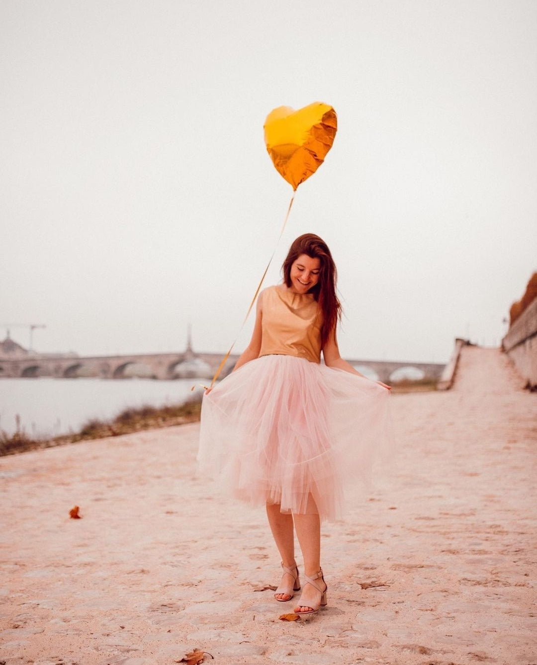 Tutu en tulle de soie rose pastel porté par une femme enceinte à la lumière du jour sur la plage. 