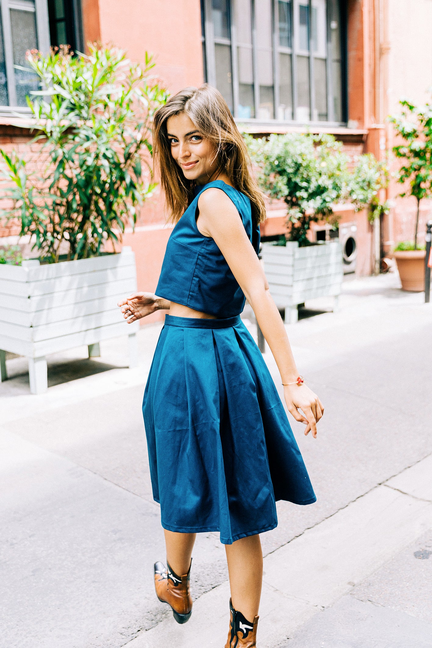 Ensemble 'Lucile' avec jupe à plis et crop-top sans manches en piqué de coton bleu canard, porté par un modèle vue de dos